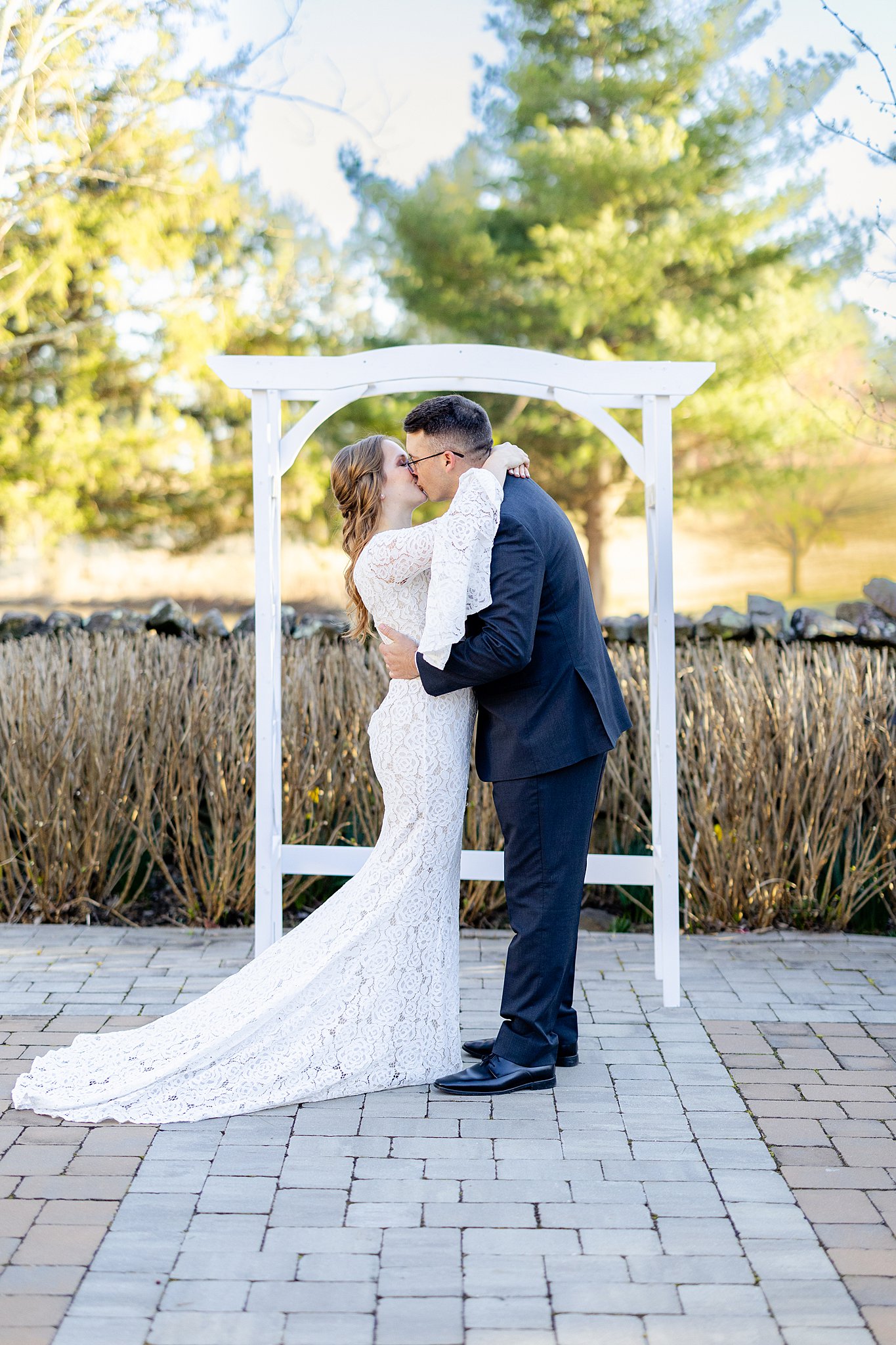 Newlyweds kiss under a pergola arch on a stone patio inside a garden virginia elopement