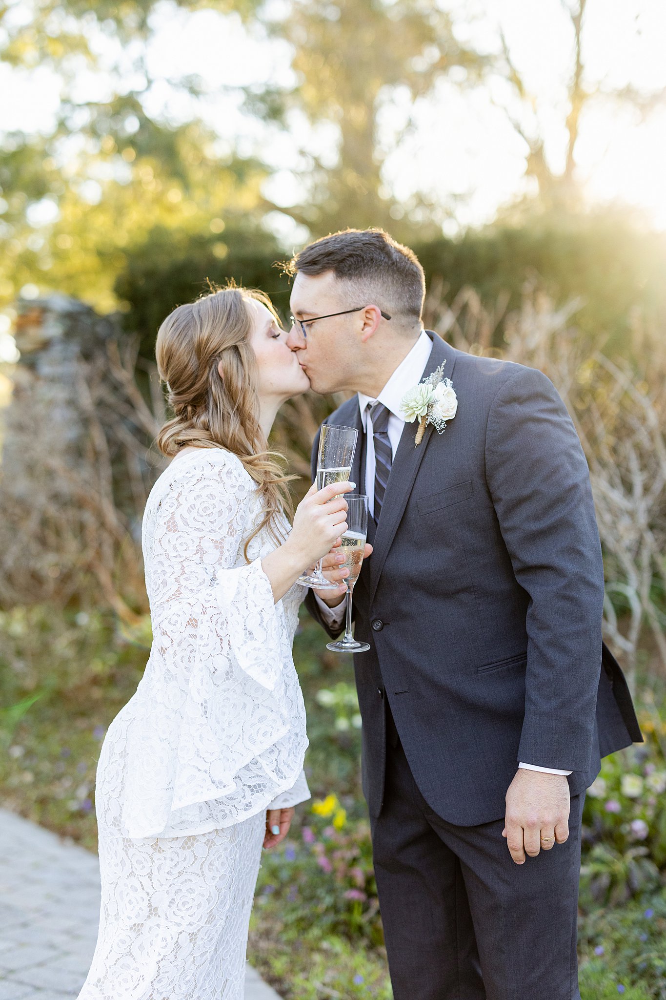Newlyweds kiss with champagne in a stone walled garden