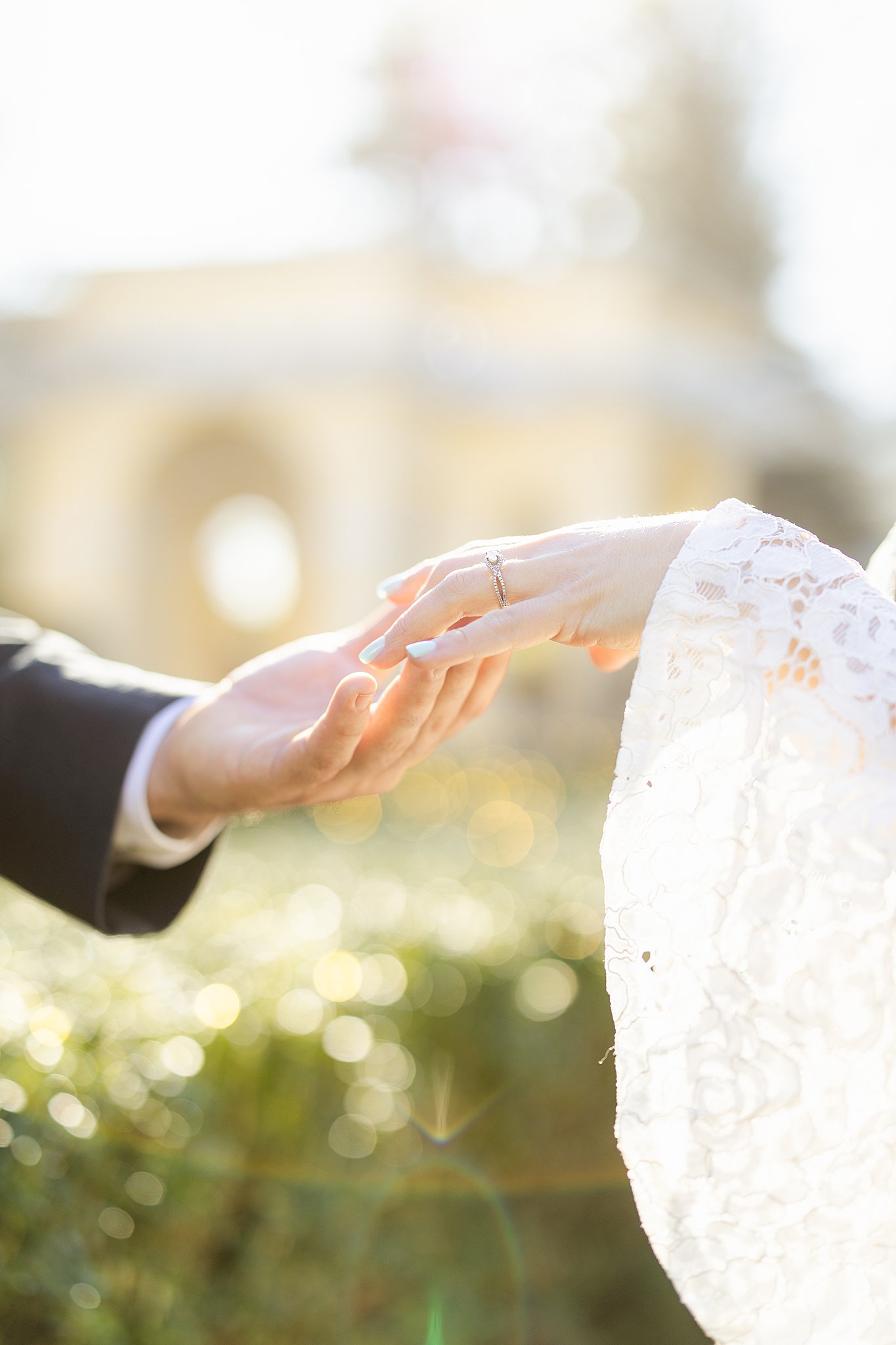 Newlyweds hold hands outside in a lace dress