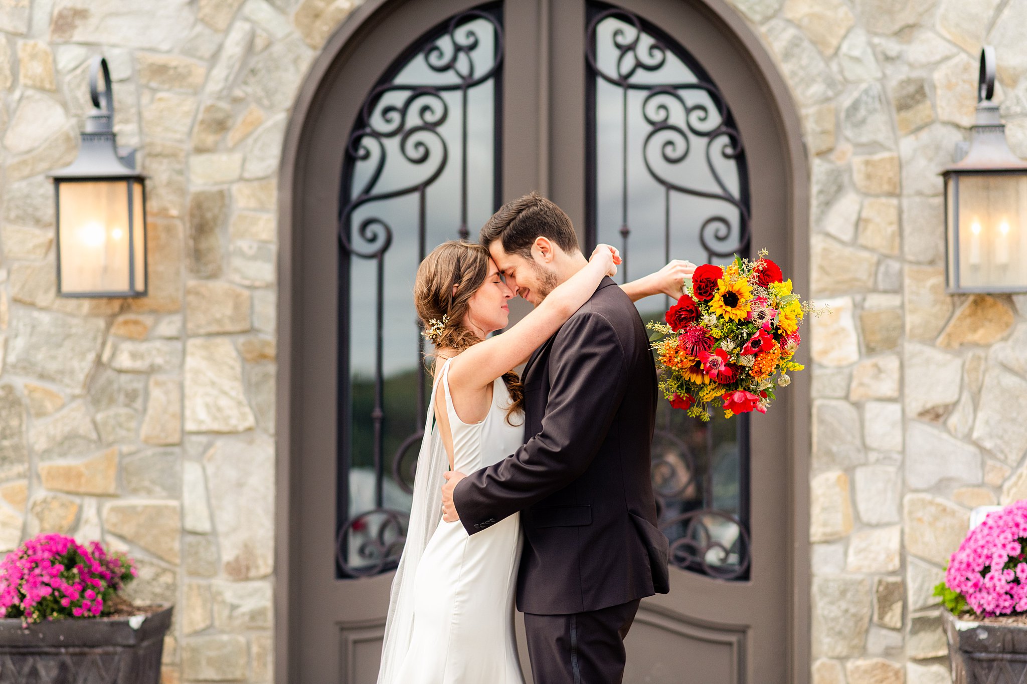 Newlyweds hug in front of a grand entry door framed in stone walls virginia wedding planner