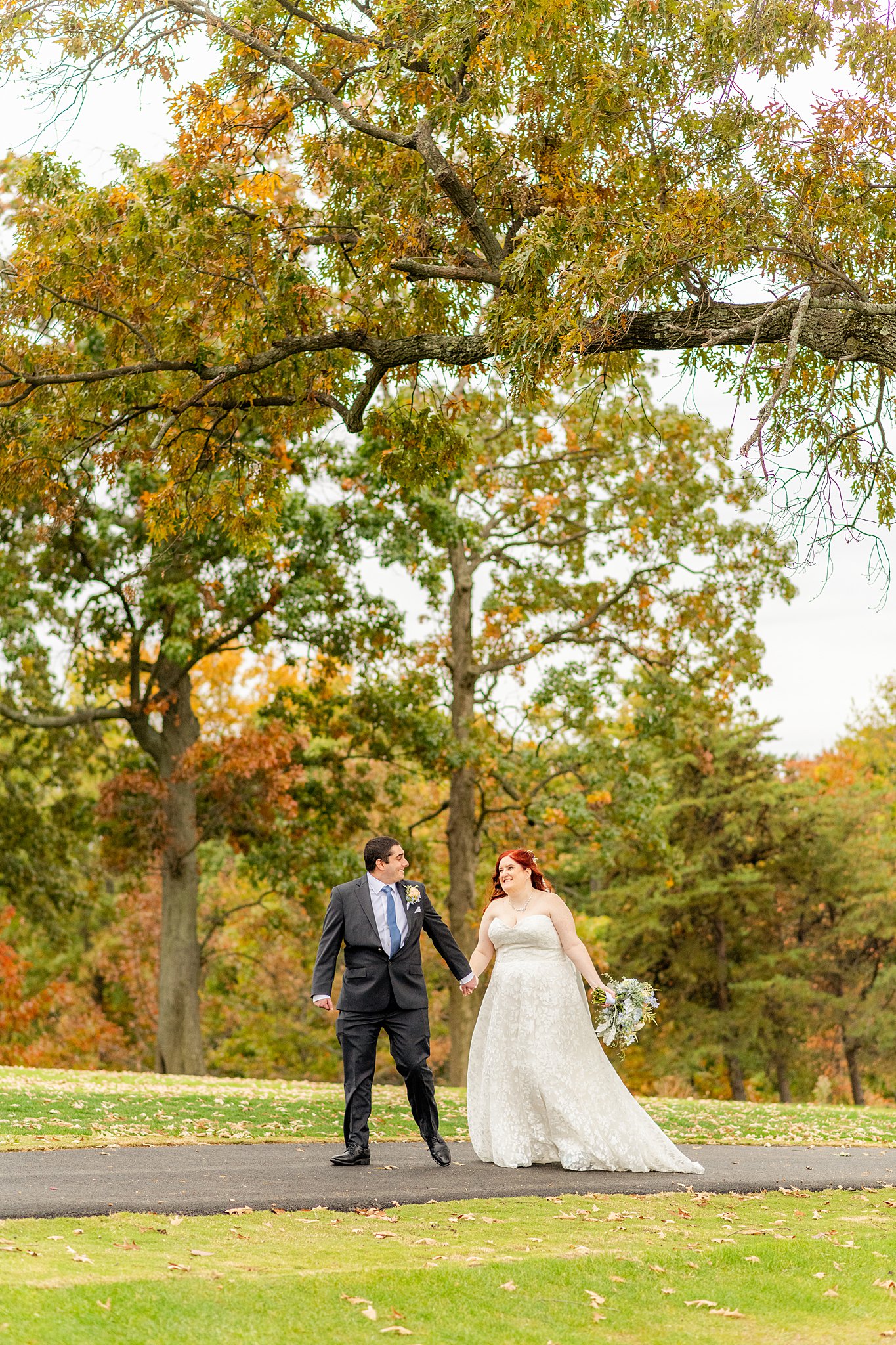 NEwlyweds walk down a paved sidewalk in a large park virginia wedding planner